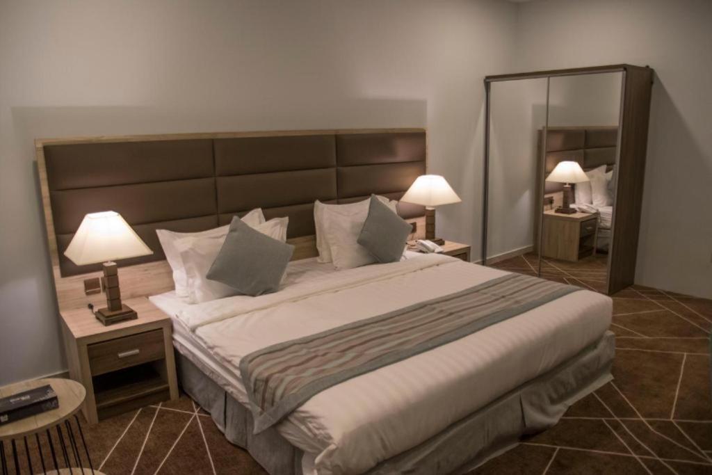 塔伊夫Fiori Hotels的一间卧室配有一张大床、两盏灯和一面镜子