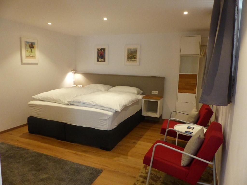 因斯布鲁克Gstill-4-Living的一间卧室配有一张床和两张红色椅子