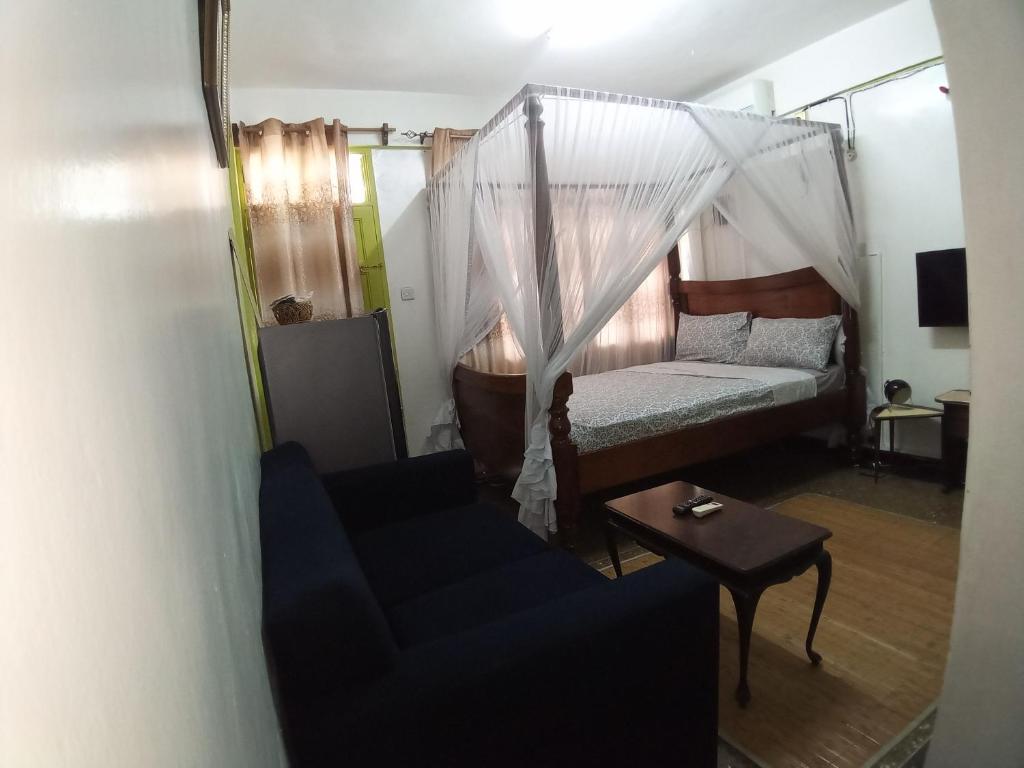 蒙巴萨SAFI Apartment的一间卧室配有一张床、一张沙发和一张桌子
