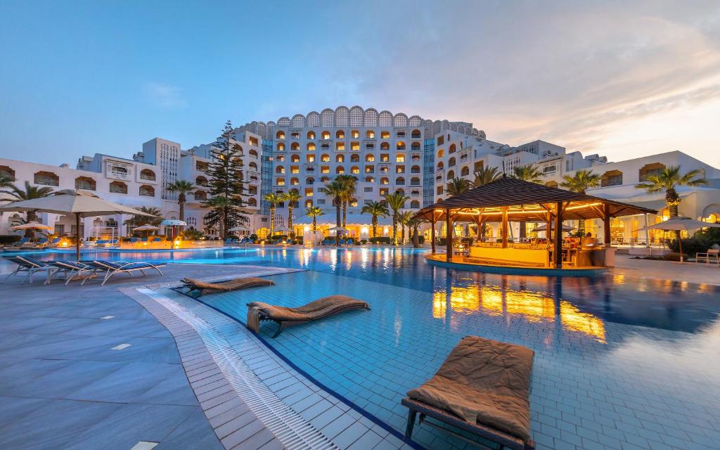 甘达坞伊港马哈巴宫酒店的一个带两把椅子的游泳池和一间酒店