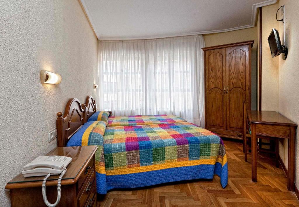纳赫拉希斯潘诺旅馆的一间卧室配有一张床和一张桌子及电话