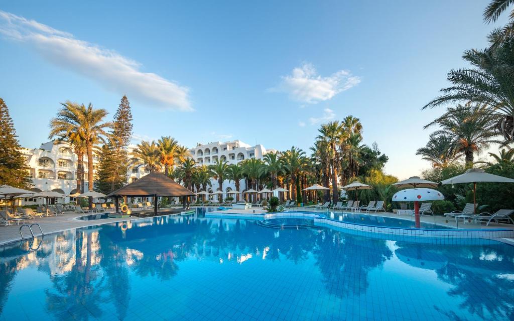 苏塞马哈巴海滩酒店的度假村的游泳池拥有棕榈树和遮阳伞
