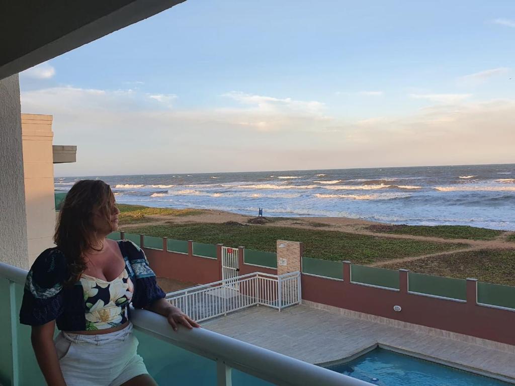 卡波布里奥Apartamento Vista Mar – Pé na Areia的站在一个海景阳台上的女人