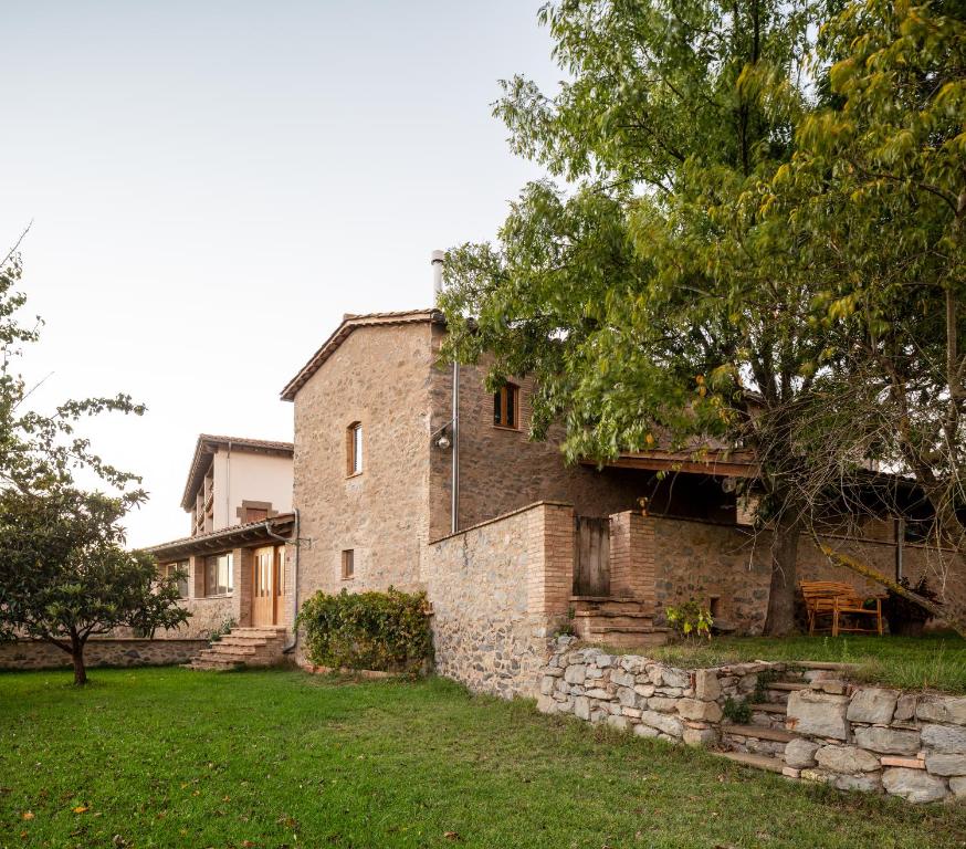 Sant Pere de TorellóEl Rebastral - Mas Vinyoles Natura的一座老砖房子,有树和院子