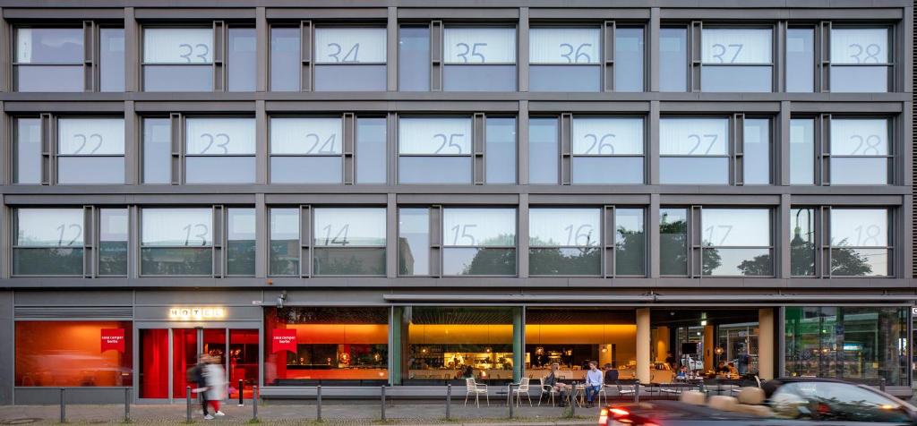 柏林柏林凯撒学院酒店的一座拥有许多窗户的建筑,前面有一辆汽车