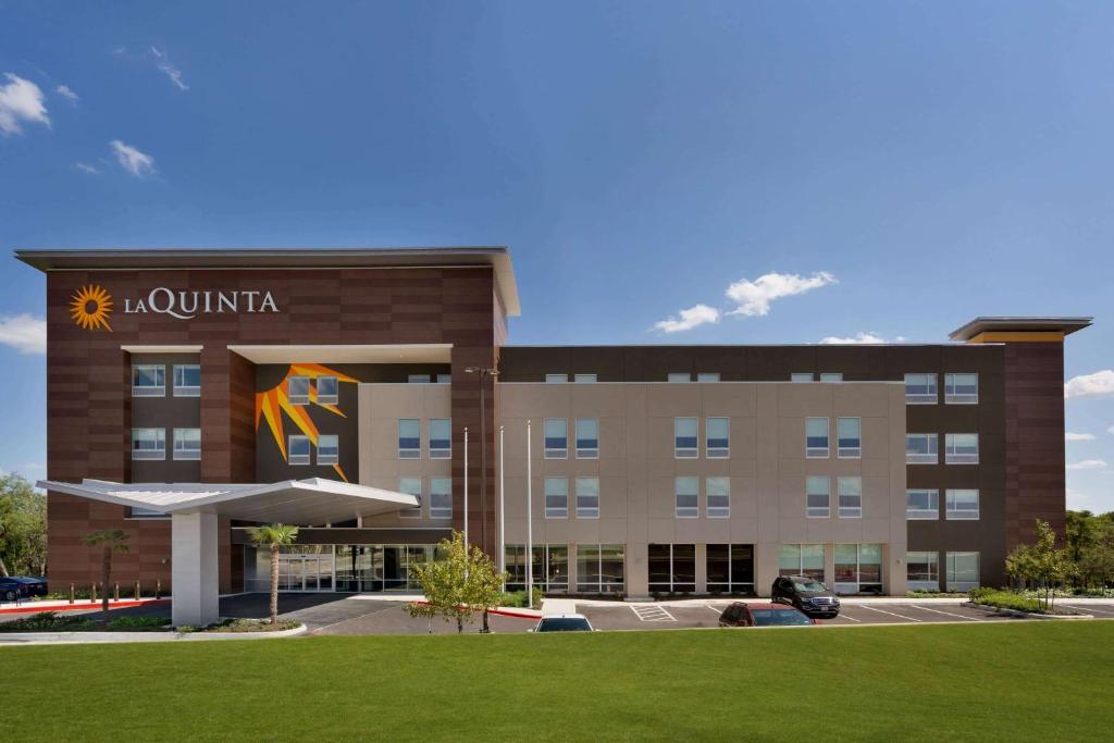 圣安东尼奥La Quinta Inn & Suites by Wyndham San Antonio Seaworld LAFB的酒店大楼前面设有草坪