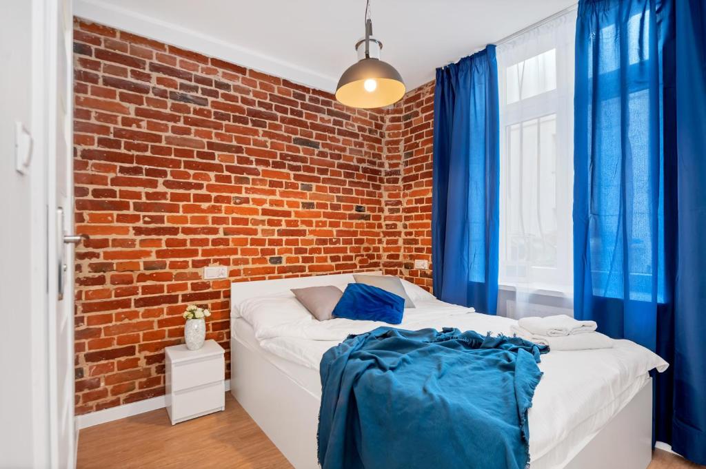 罗兹Drukarnia Apartments的一间卧室设有砖墙和一张床