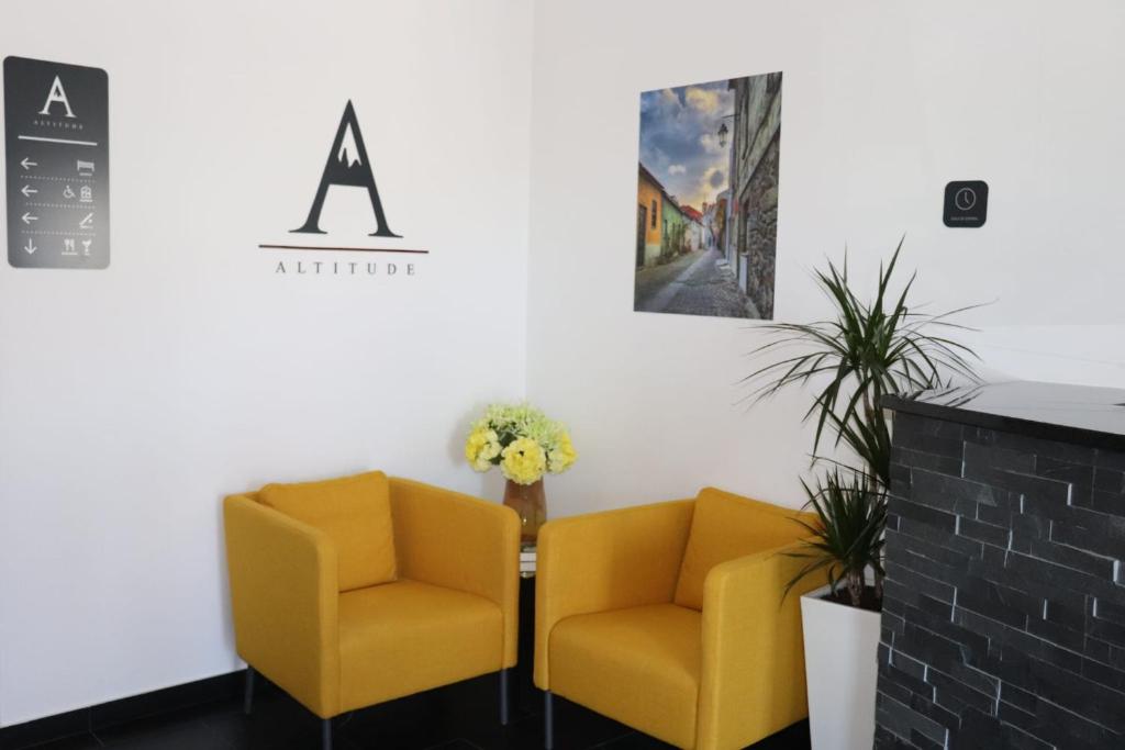 贝尔蒙特Altitude Alojamento e Restauração的两个黄色椅子坐在等候室的桌子旁
