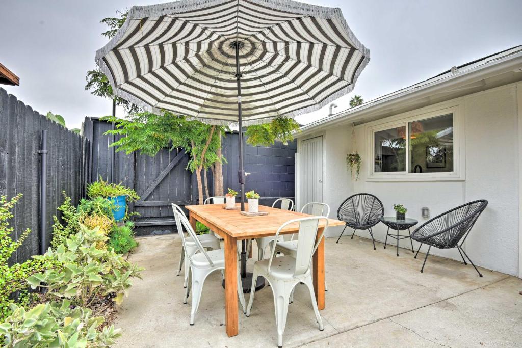 文图拉Chic and Central Ventura Home - Walk to Beach!的庭院里配有一张带椅子和遮阳伞的木桌