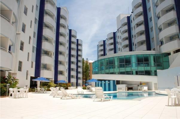 热河市Águas da Serra Apart Hotel的庭院设有椅子,大楼前设有游泳池