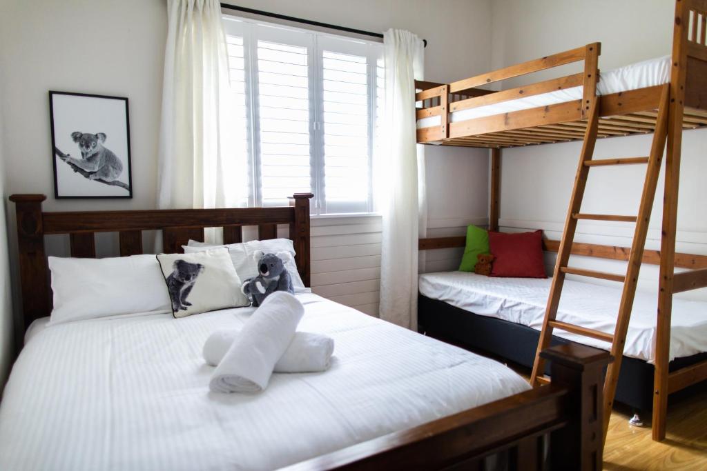 肯图巴WildLife Lodge Katoomba的卧室配有2张双层床和白色床单