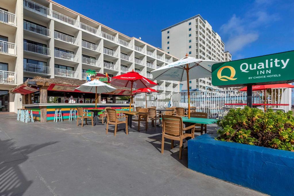大洋城波德瓦克品质酒店的大楼前带桌子和遮阳伞的天井