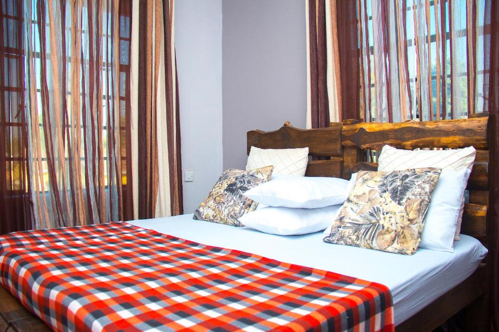 阿鲁沙MINA CHAI HOUSE BNB的一张带 ⁇ 子毯子和枕头的床