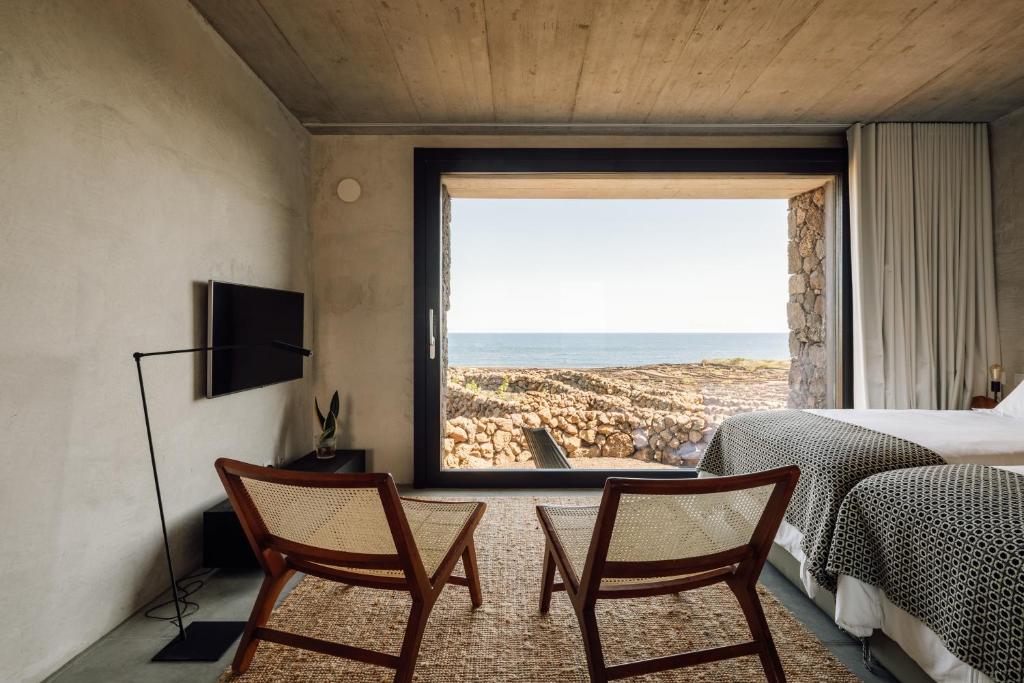 Cais do MouratoAzores Wine Company的一间带两把椅子的卧室,享有海景