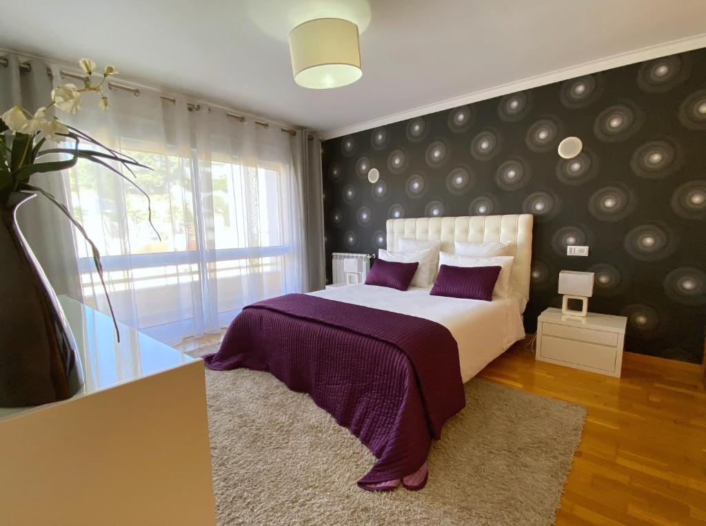 帕雷迪Jardins da Parede 211的一间卧室配有一张带紫色床单的床和窗户。
