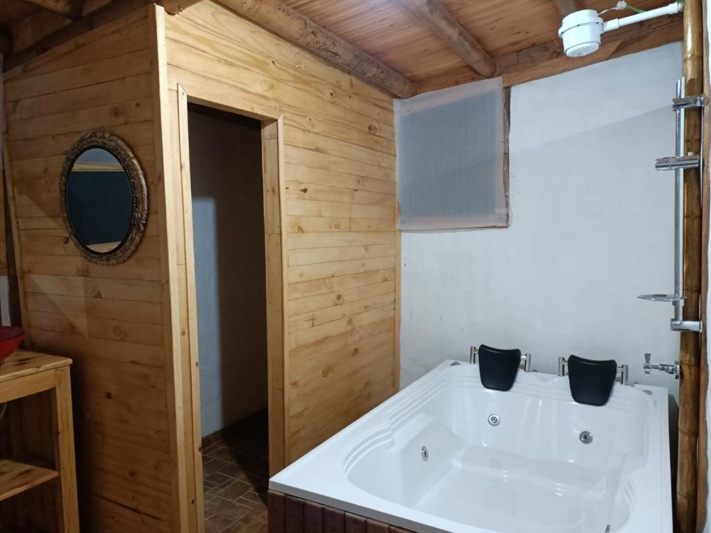 FómequeEl Refugio del Oso de Anteojos的浴室配有白色浴缸和木墙