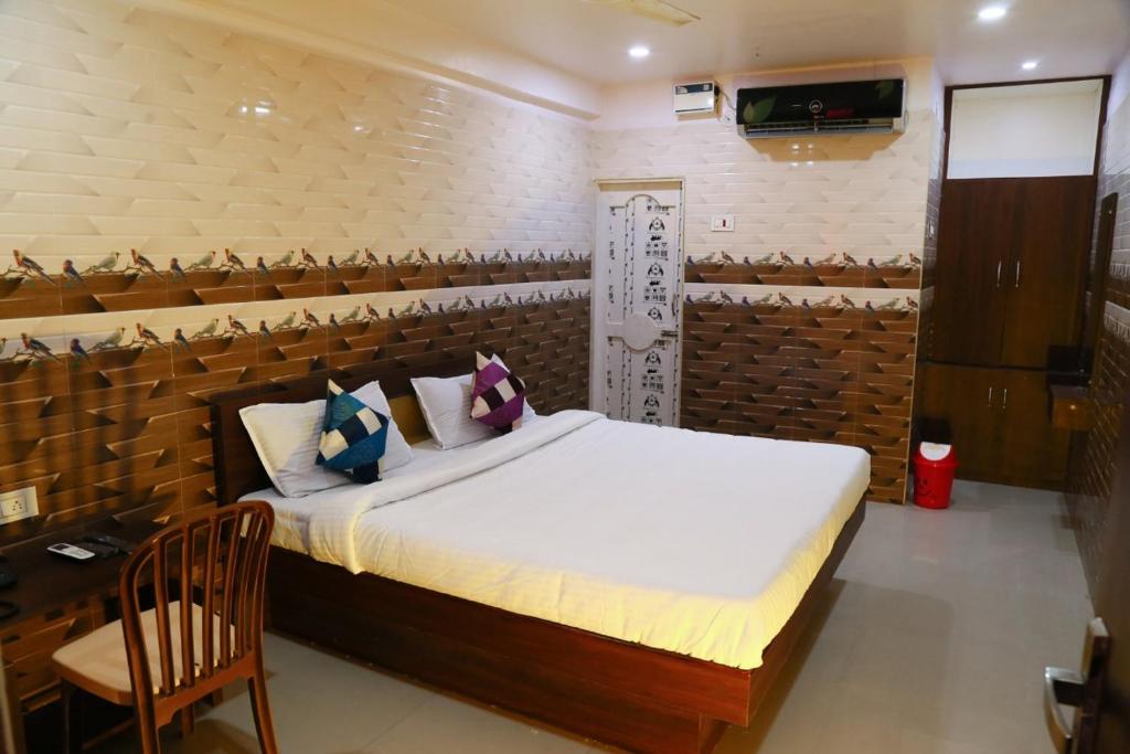ArakkonamSri Mahalakshmi Deluxe Lodging Arakonam的一间卧室,卧室内配有一张床和一把椅子