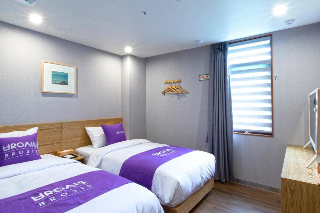 釜山Brosis Hotel的酒店客房设有两张床和窗户。