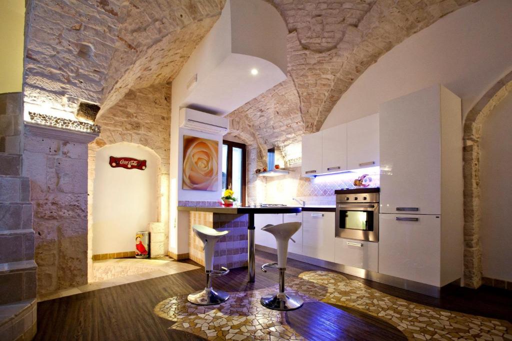 普蒂尼亚诺L'Angolo di Gaudì, casa Milà的厨房配有白色橱柜和石墙