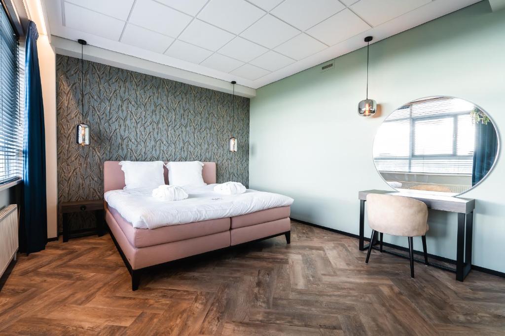 埃因霍温Onderwijshotel De Rooi Pannen Eindhoven的卧室配有1张床、1张桌子和1把椅子
