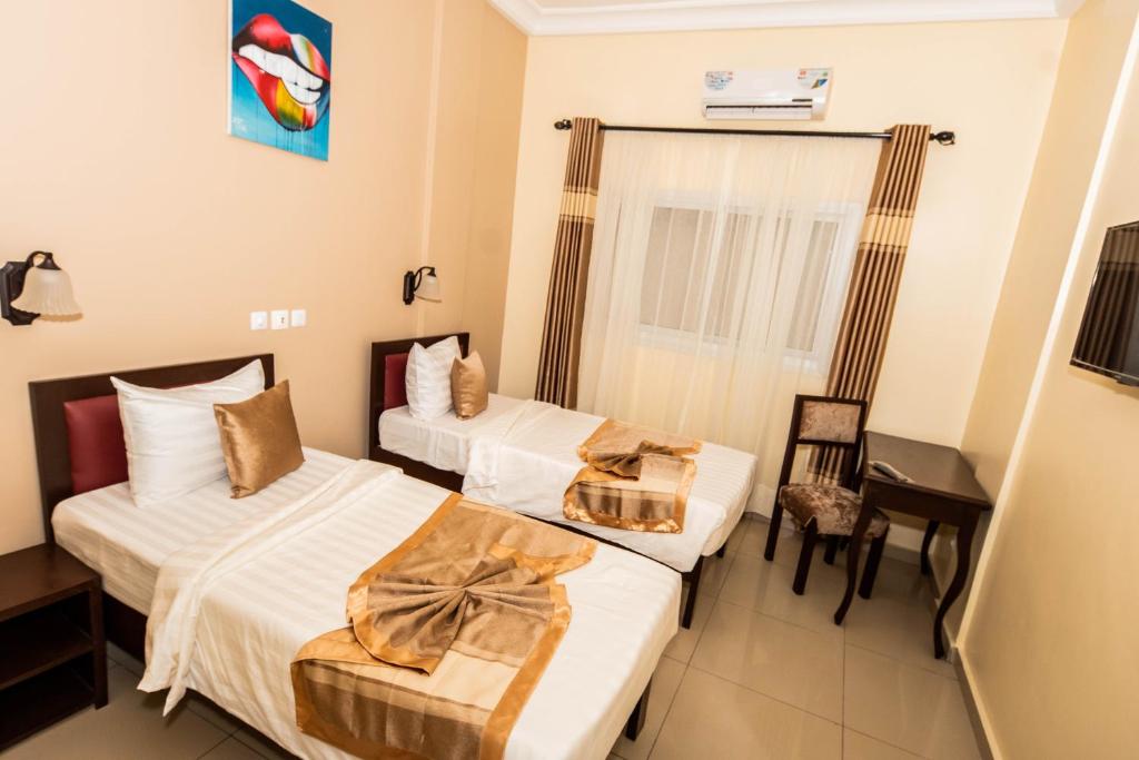 雅温得ISIS Hôtel的酒店客房配有两张床和一张书桌