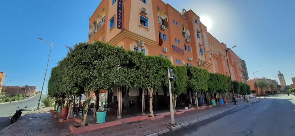 瓦尔扎扎特玛尔玛酒店的一条街道前方树木繁茂的橙色建筑