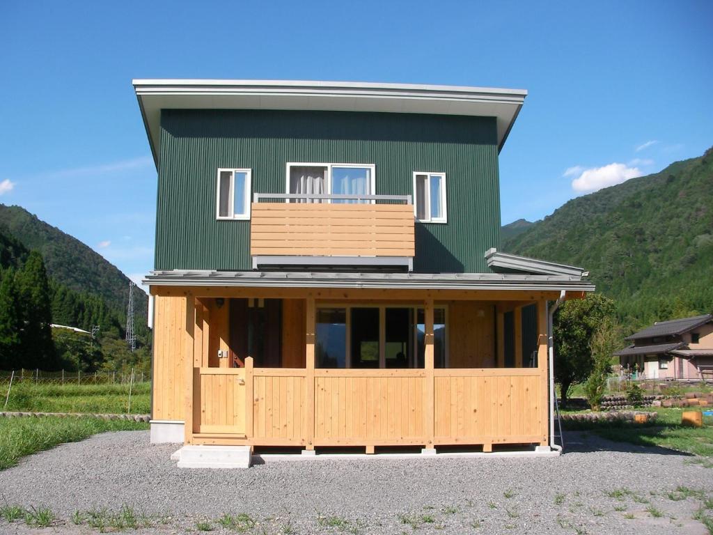 郡上市Gujo Cottage Ryukobashi no Hotori - Vacation STAY 88697v的绿色房子,设有门廊和阳台