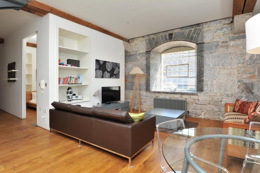 普里茅斯Drakes Wharf @ Royal William Yard的客厅设有真皮沙发和石墙