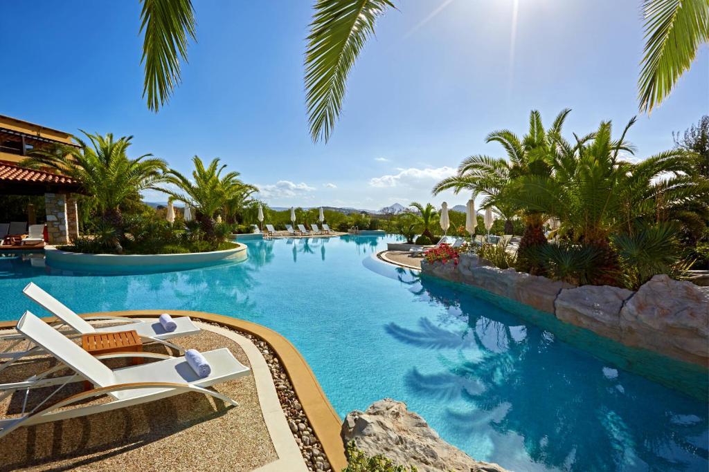 Romanu威斯汀克斯塔纳瓦里诺酒店的一个带椅子和棕榈树的度假村游泳池