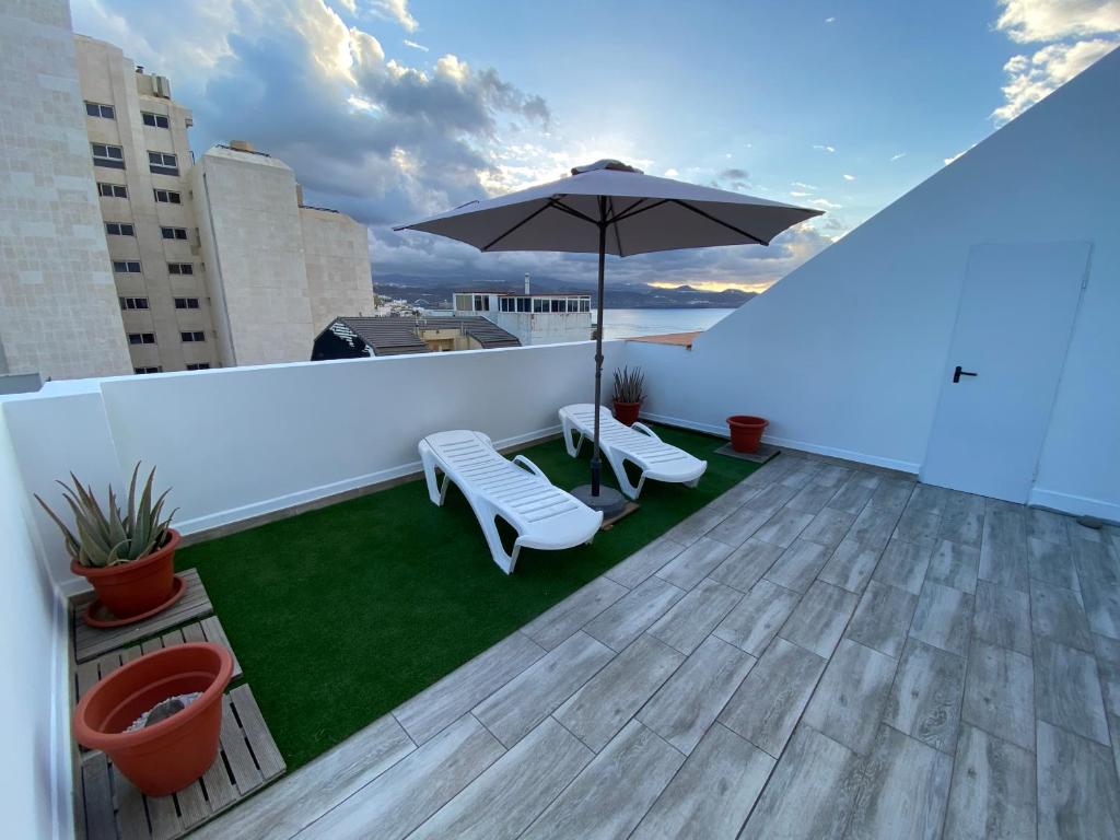 大加那利岛拉斯帕尔马斯Holiday Home & Rooftop Lounge的屋顶上带遮阳伞和椅子的天井