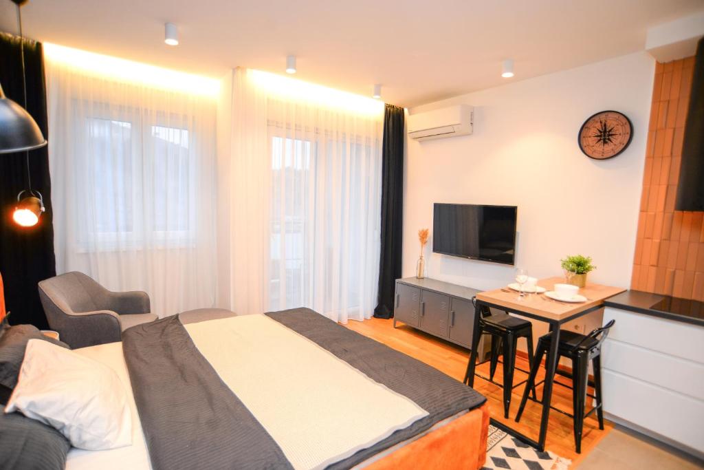 波德戈里察Design Apartment near Gorica Park的一间卧室配有一张床铺和一张桌子,还设有一间厨房
