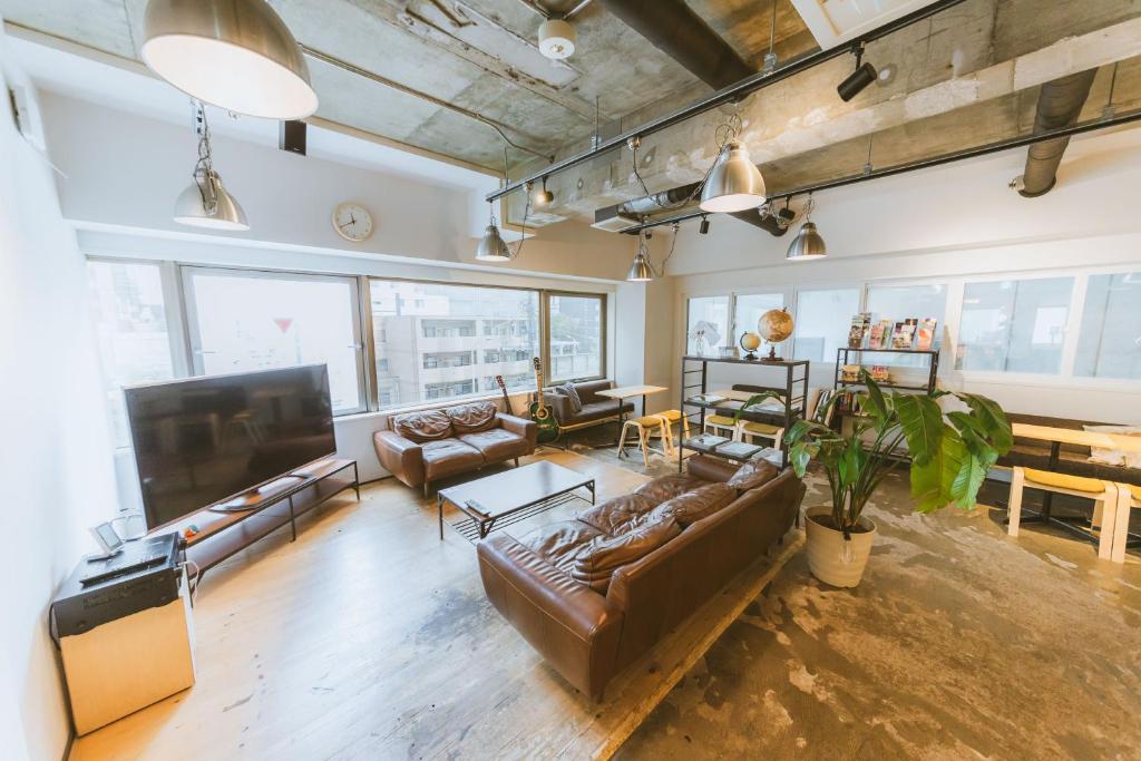 札幌札幌青年旅舍的客厅配有真皮沙发和平面电视