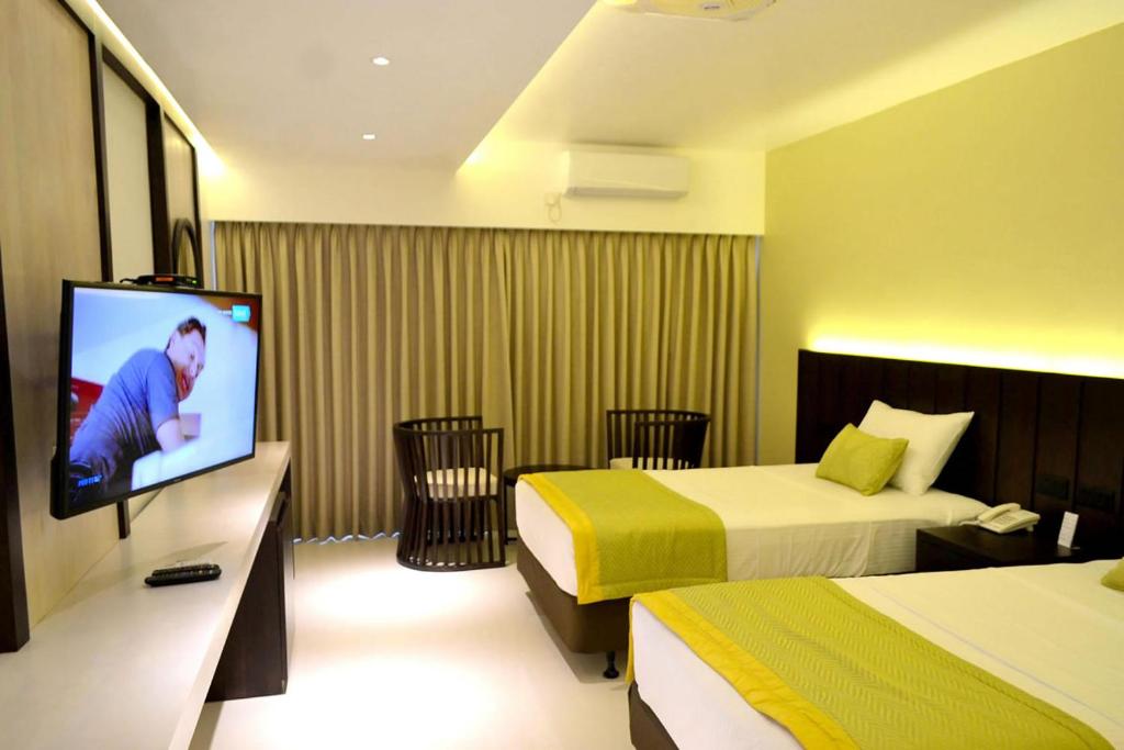 卡图纳耶克Good wood Airport Hotel的酒店客房设有两张床和一台平面电视。