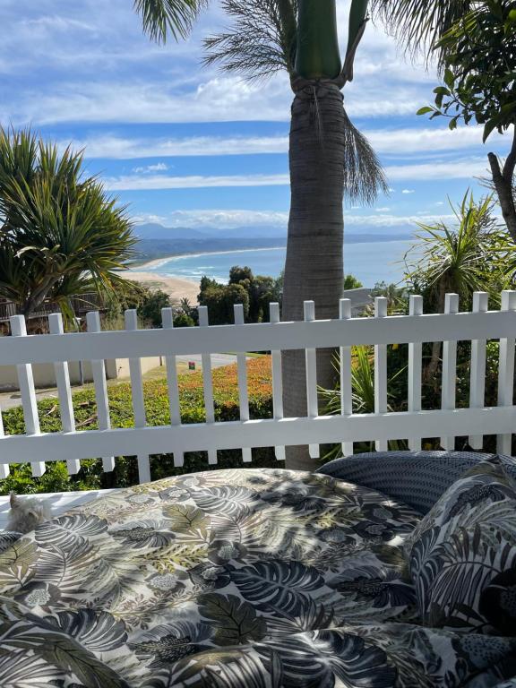 普利登堡湾Plett Holiday Stay with Pizza Oven and Views的白色的围栏,有桌子和棕榈树