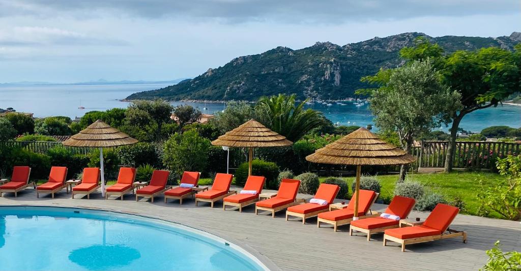 维琪奥港Hôtel Alivi Di Santa Giulia的游泳池旁的一排椅子和遮阳伞