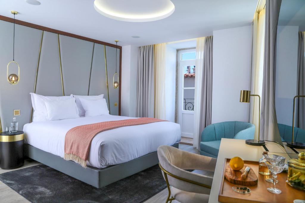 里斯本São Vicente Alfama Hotel by TRIUS Hotels的酒店客房带一张床、一张桌子和椅子