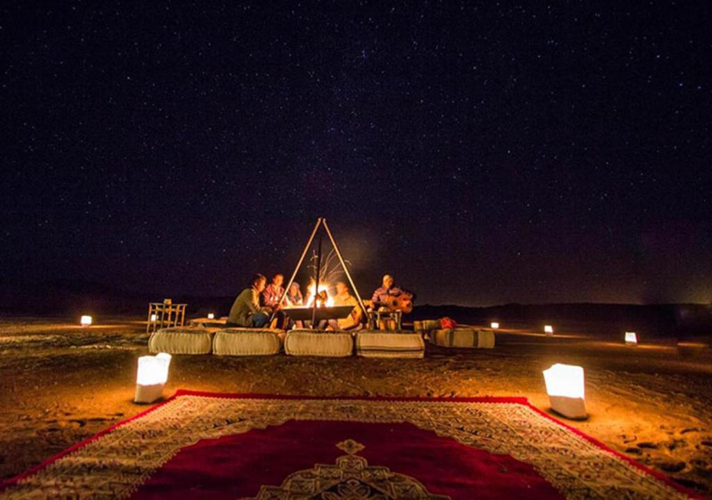 扎古拉Sahara Relax Camps的一群人晚上坐在火炉旁