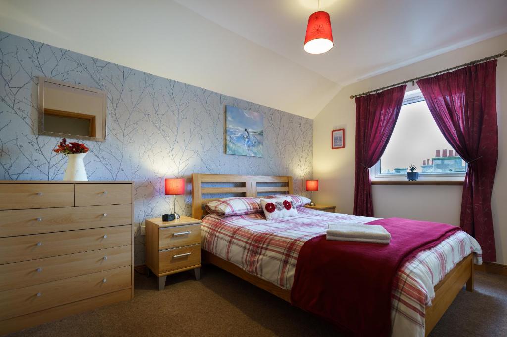 洛西茅斯Lossiemouth Haven的一间卧室配有一张床、一个梳妆台和一扇窗户。