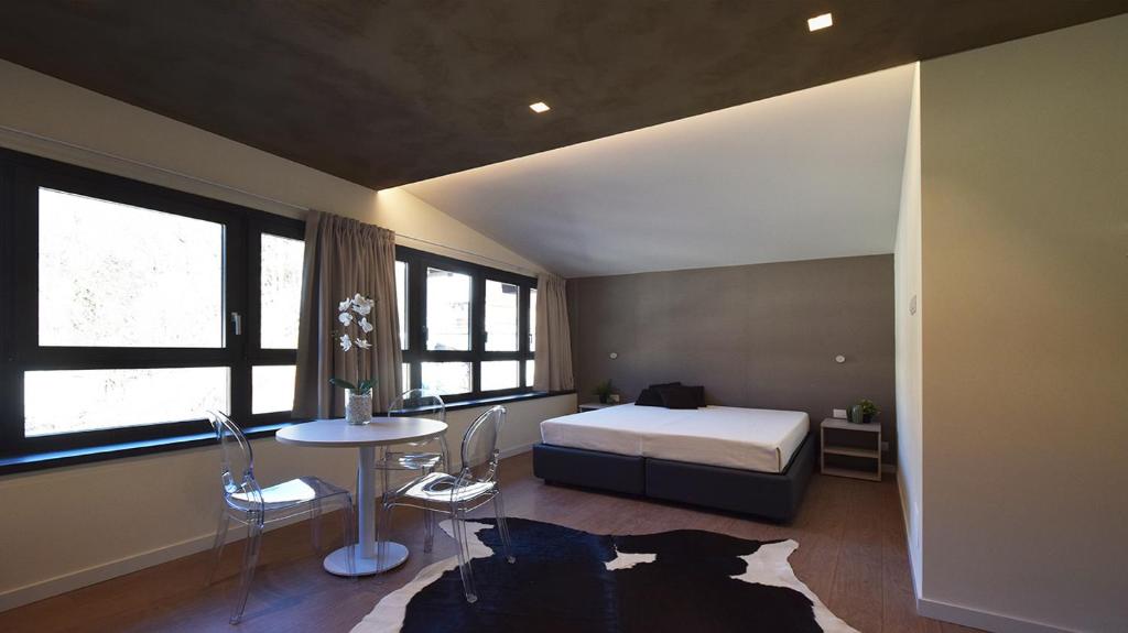 克里索洛La Meira Sermig Casa Ferie的一间卧室配有一张床、一张桌子和一些窗户