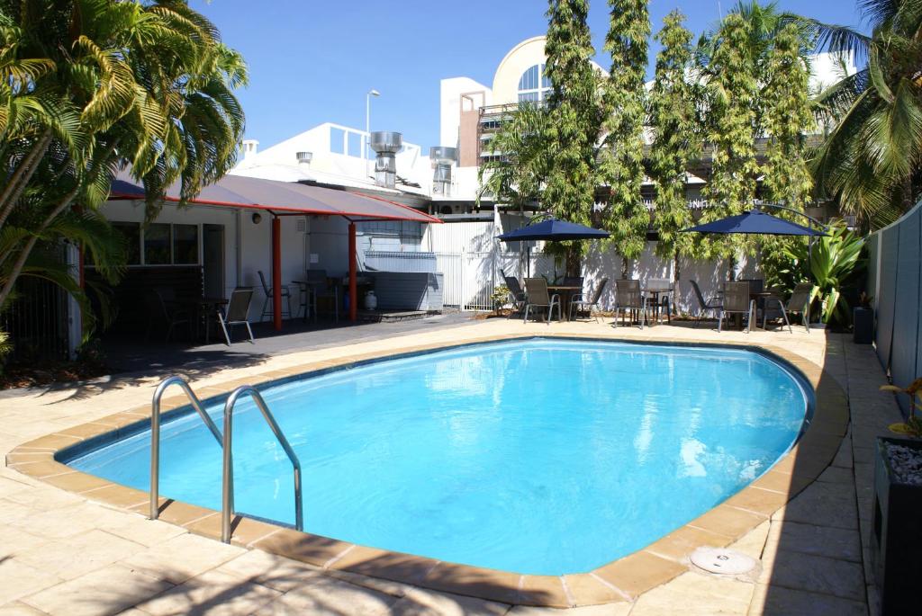 达尔文Darwin Poinciana Inn的一个带椅子和遮阳伞的大型蓝色游泳池