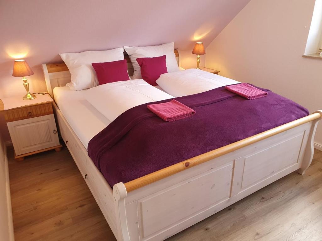 翁德洛Haus Petersen的一张白色大床,配有紫色床单和枕头