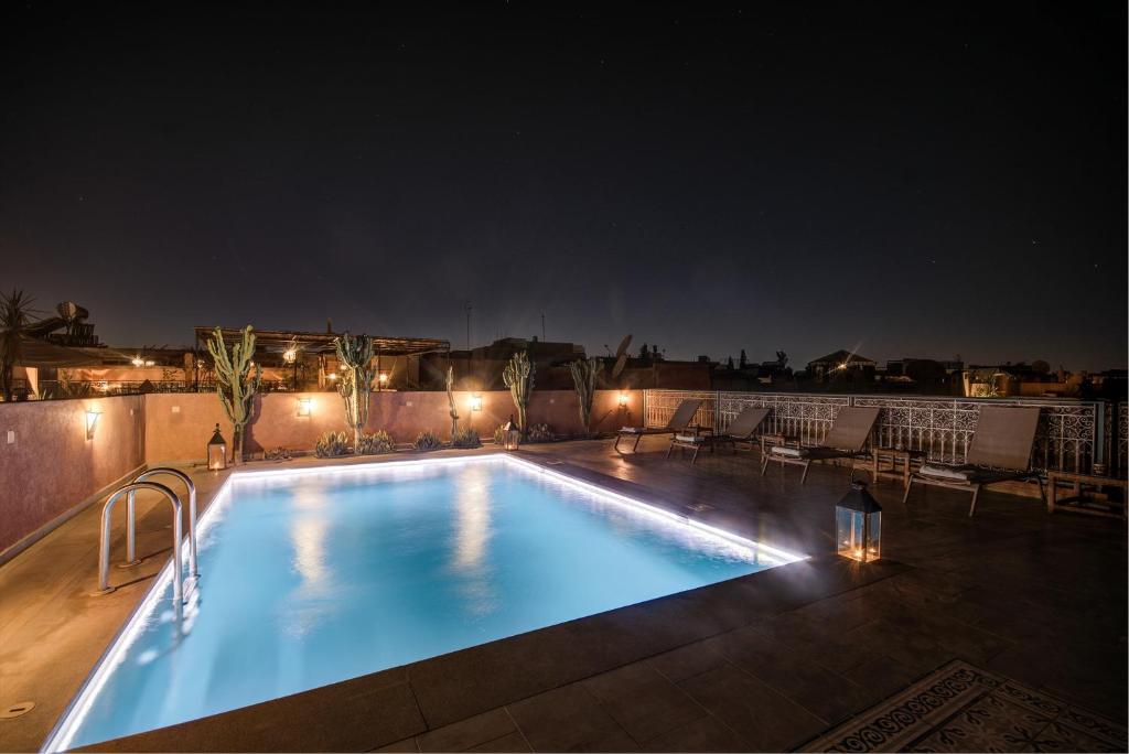 马拉喀什Riad Les Oliviers & Spa的屋顶上灯光照亮的游泳池