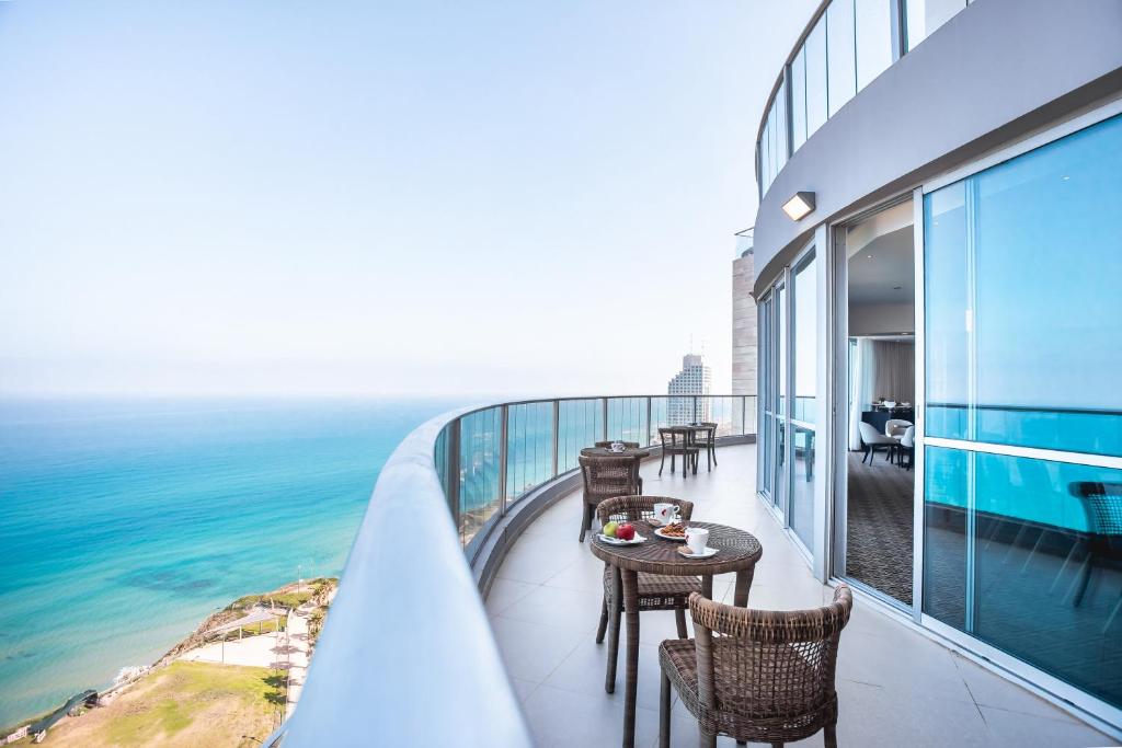 内坦亚Ramada Hotel & Suites by Wyndham Netanya的一个带桌椅的海景阳台