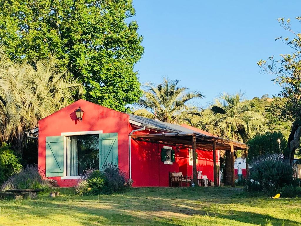 米纳斯Casa de campo - retiro con encanto en las sierras的一座棕榈树下的红色房子