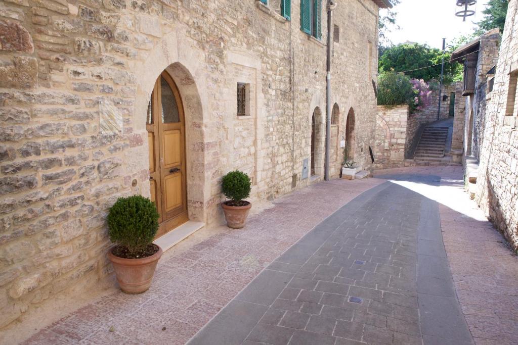 阿西西LE DIMORE ARCANGELO Giuseppe的一条种植了两株盆栽植物的小巷和木门