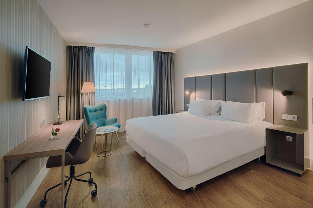 布拉尼亚克NH Toulouse Airport的酒店客房设有一张白色大床和一张书桌