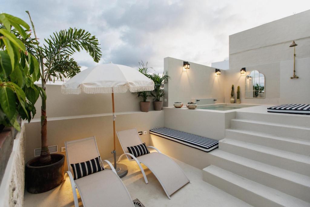 大加那利岛拉斯帕尔马斯La Colonial Suites Apartamentos de Lujo的庭院配有两把椅子和一把遮阳伞