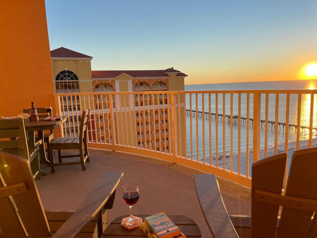 巴拿马城海滩Calypso 3-2303 Penthouse Level w/ Incredible View!的阳台配有桌子和一杯葡萄酒