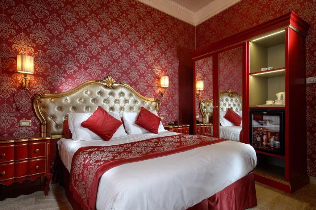 威尼斯卡纳莱托酒店的一间卧室设有一张带红色墙壁的大床
