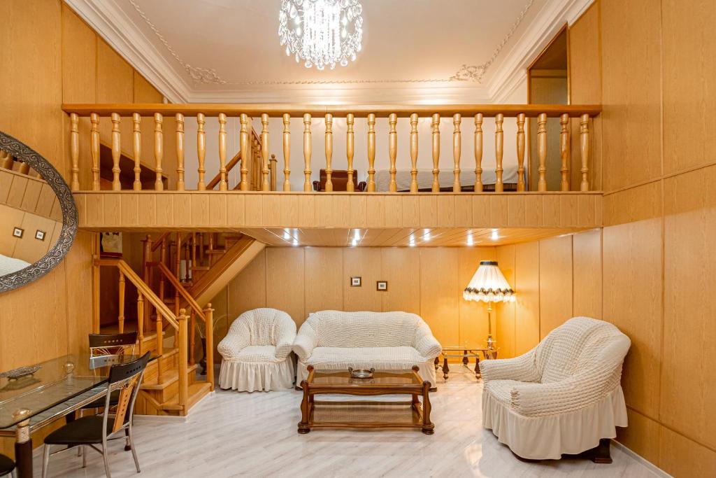 第比利斯Rustaveli Downtown ApartHotel的一间带两把椅子和楼梯的客厅